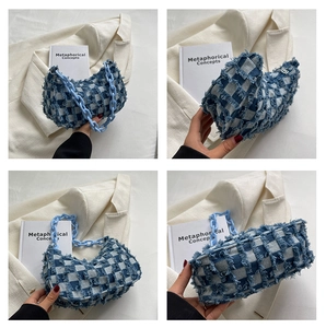Detail van blauw-witte geruite denim baguette tas met franjes en een grove ketting