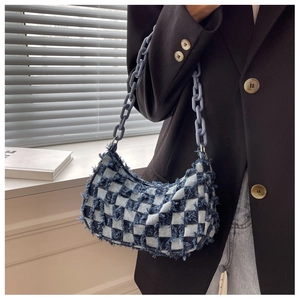 Detail van blauwe denim tas met ruitpatroon, rafelige randen en dikke plastic ketting