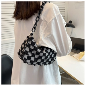 Detail van geruite tweed hobo tas met franjes en een grove zwarte kettingriem