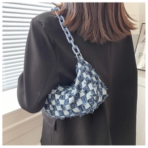 Detail van blauwe geruite denim hobo tas met franje randen en matte kettingriem