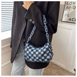 Detail van blauwe denim tas met schaakbordpatroon, rafelranden en kettingriem