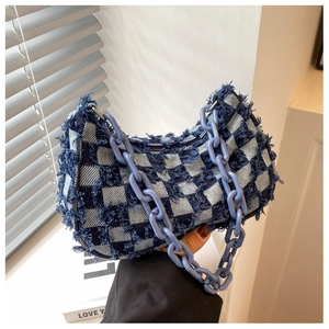 Detail van blauwe schaakbord denim handtas met gerafelde randen en dikke plastic ketting