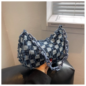 Detail van denim geruite halve maan tas met paarse dikke ketting en franje randen