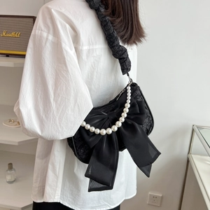 Elegant black lace shoulder bag with large chiffon bow and pearl chain strap on model