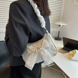 White pleated cloud shoulder bag with silk bow and pearl chain on a female model