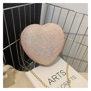 Detail of pink glitter heart-shaped crossbody bag with elegant gold chain strap