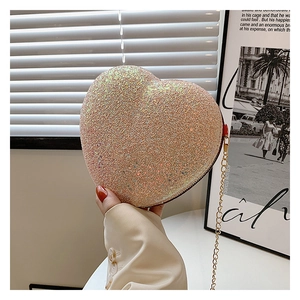 Macro view of champagne heart-shaped clutch bag with glitter texture and gold chain