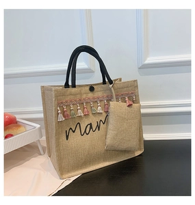 Close-up of beige linen mama tote bag with colorful tassels and black tubular handles