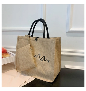 Detail of linen tote bag with mama print, black handles, and matching small pouch