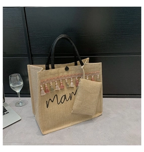 Detail of mama jute tote bag with black handles, colorful tassels and mini pouch