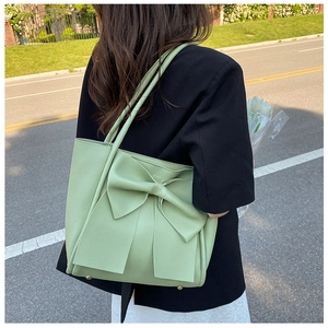 Détail du sac cabas vert clair avec un grand nœud et des rivets dorés de protection sur le fond