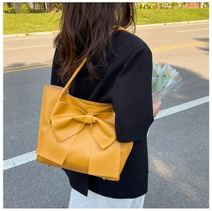 Gros plan d'un grand sac cabas jaune orné d'un nœud élégant en similicuir souple de qualité