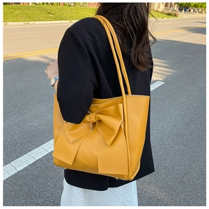 Détail du grand sac cabas jaune avec nœud décoratif et texture en similicuir mat premium