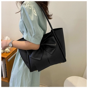 Détail des pieds en métal doré sur le sac fourre-tout en cuir noir avec nœud