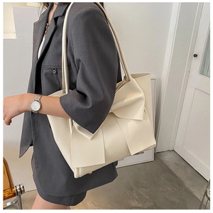 Détail d'un grand sac cabas crème avec nœud, montrant le simili cuir et les pieds de protection