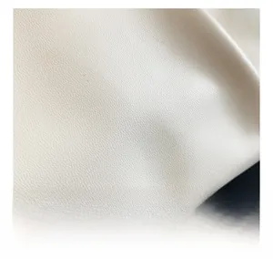 Macro detail of creamy white lychee textured leather showing soft matte finish and grain