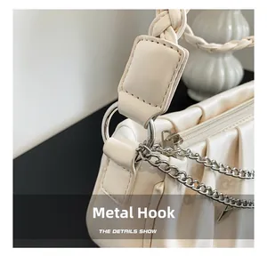 Detail of creamy white pleated handbag with woven handle and silver metal hardware hook