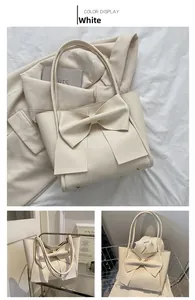 Détail macro du sac cabas blanc avec grand nœud et pieds de protection en métal doré