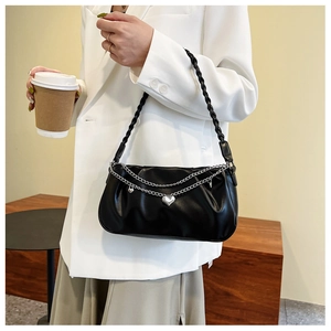 Detail of black pleated shoulder bag with silver heart charm and woven strap