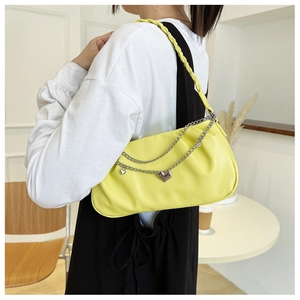 Detail of yellow pleated cloud bag with silver heart chain strap on woman shoulder