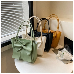 Détails de quatre sacs cabas colorés à grands nœuds dans un décor de bureau élégant