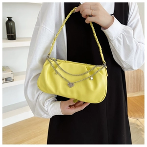 Detail of yellow pleated shoulder bag with woven handle and silver heart chain charm