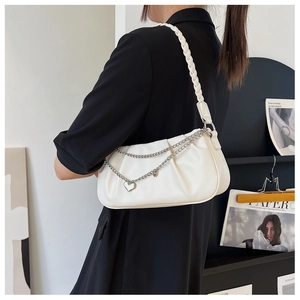 Detail of white pleated moon bag with woven strap and silver heart chain charm