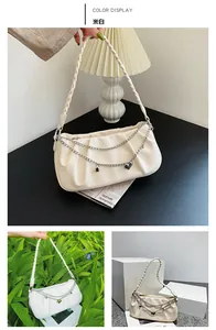 Detail of cream white underarm bag featuring ruched texture and dual metal chain charms