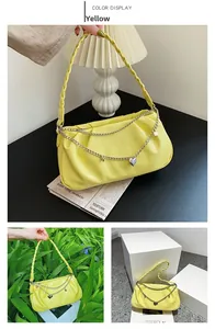 Detail of yellow pleated underarm bag with woven handle and double silver heart chains
