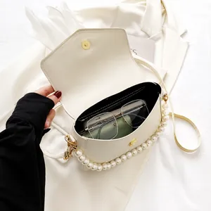 Vista detallada del bolso blanco con cadena de perlas y capacidad del espacio interior