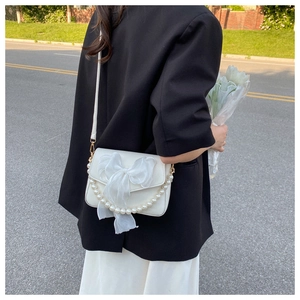 Detail of white PU leather crossbody bag with oversized organza bow and pearl handle