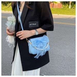 Detail of light blue crossbody bag with large organza bow and pearl chain decoration