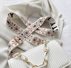 Detail of white textured handbag featuring thick resin chain and floral woven strap