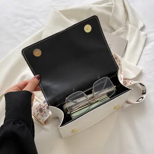 Interior view of white crossbody bag showing storage space for phone and glasses