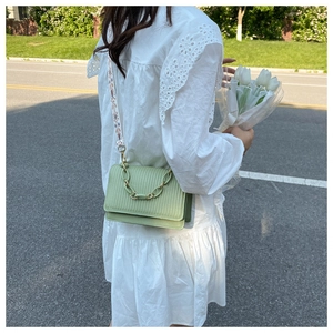 Detail of mint green crossbody bag with vertical textures and patterned wide strap