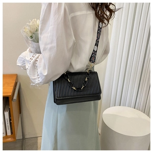 Detail view of black pleated crossbody bag with thick chain and patterned strap