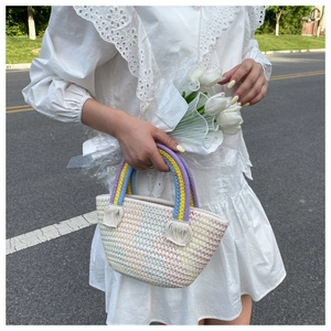 Close-up of rainbow woven handle and decorative tassel on a handmade crochet tote bag