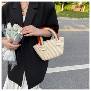Detail of woven straw bag with rainbow colored handle and white fringe tassel detail