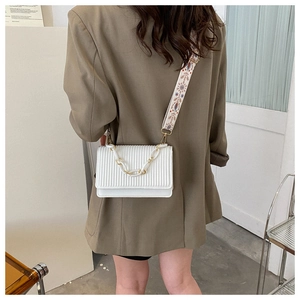 White pleated crossbody bag featuring a chunky gold chain and ethnic embroidered strap