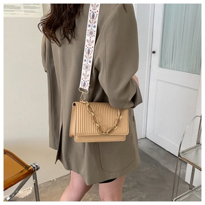 Detail of khaki pleated shoulder bag with floral jacquard strap and metal chain