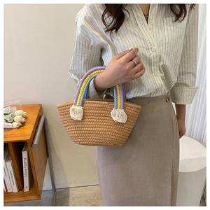 Detail of woven straw handbag with rainbow braided handle and fringe tassels