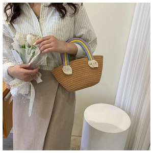 Detail of woven beach tote with rainbow handles, white tassels, and neutral straw texture