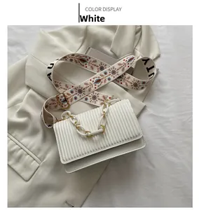 Detail of white pleated shoulder bag featuring acrylic chain and floral strap