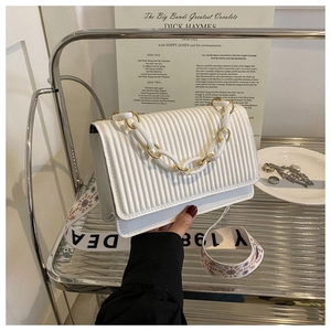 Detail of white pleated handbag with chain handle and floral embroidered wide strap