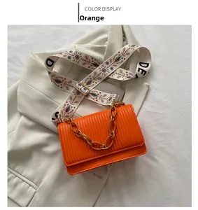 Detail of orange textured shoulder bag with chunky chain and floral embroidery strap