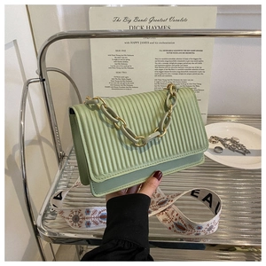 Detail of mint green pleated crossbody bag with embroidered and gold chain straps