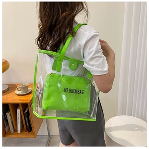 Detail of transparent PVC tote with neon green inner bag worn over the shoulder