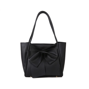 Sac fourre-tout noir avec un grand nœud et de longues anses sur fond blanc éclatant