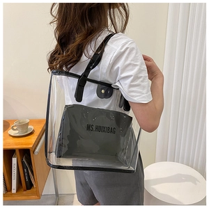 Close-up of large transparent PVC tote bag with black leather straps and inner pouch