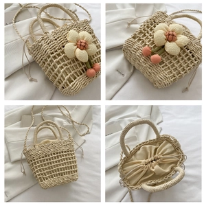 Close-up of woven straw bucket bag featuring plush floral charms and a drawstring closure